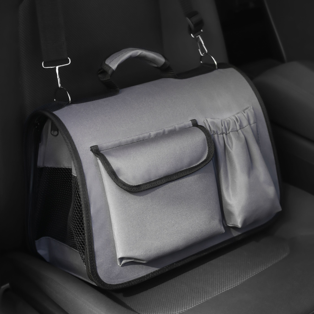 Серая сумка-переноска для животных стоит на пассажирском сиденье.